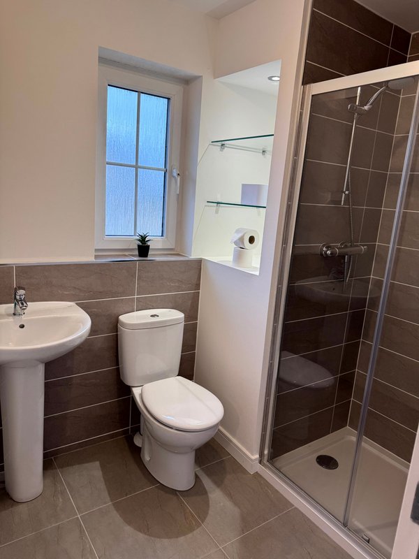 Modern bathroom with toilet, pedestal sink, shower cubicle and window