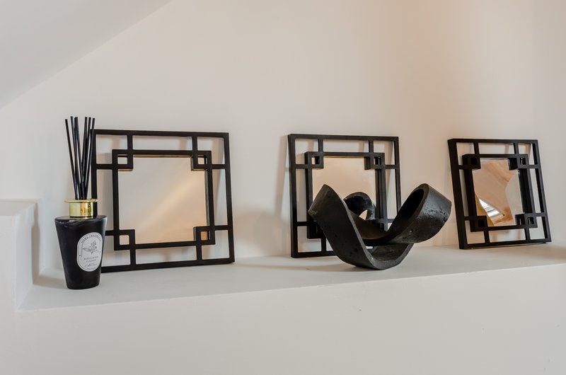 Shelf with decorative black frames, black sculptural vessel, candle and reed diffuser