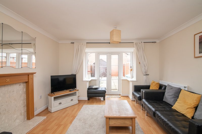Bright living room with black sofa, wooden coffee table, TV, fireplace and patio doors