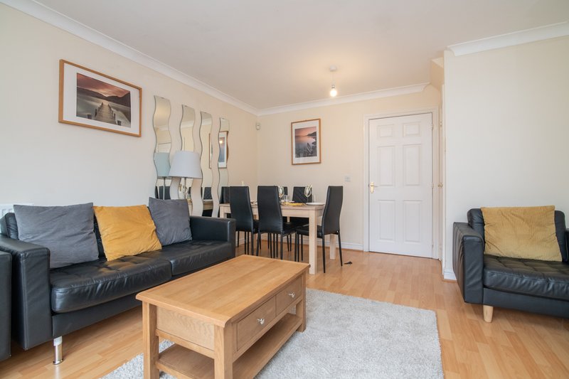 Open-plan living room with leather sofas, wooden coffee table, dining area and hardwood flooring