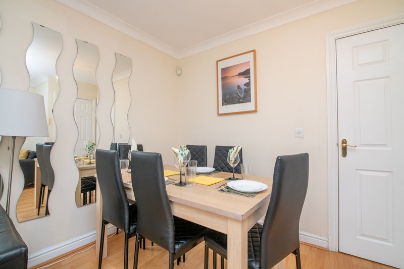 Dining room with wooden table, black chairs, decorative mirror and framed artwork on wall