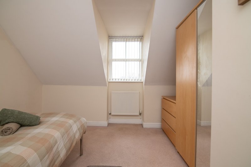 Attic bedroom with single bed, wooden chest of drawers and skylight window