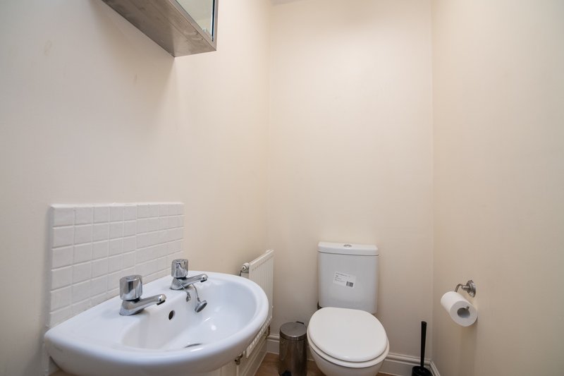 Small bathroom with white sink, toilet, tile backsplash and mirror above