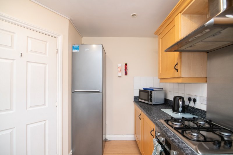 Modern kitchen with wooden cabinets, gas hob, stainless steel fridge and countertop appliances