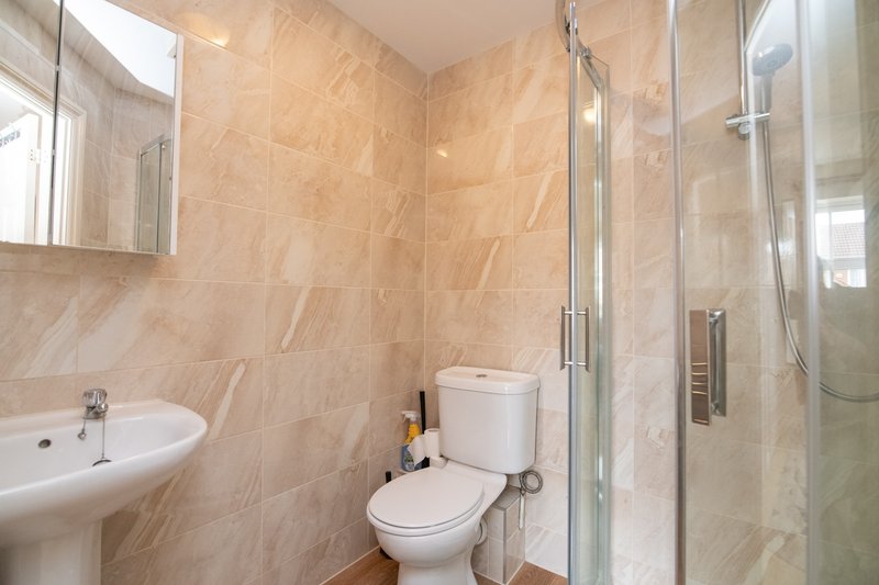 Modern bathroom with beige tile walls, sink, toilet, mirror and walk-in shower