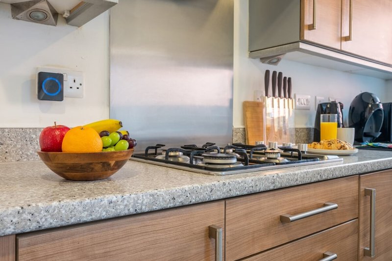 Modern kitchen with gas hob, fruit bowl, and stainless steel appliances