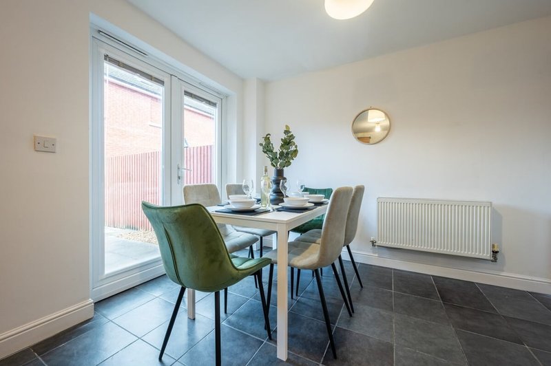Modern dining room with table, four chairs, glass doors to patio, and radiator