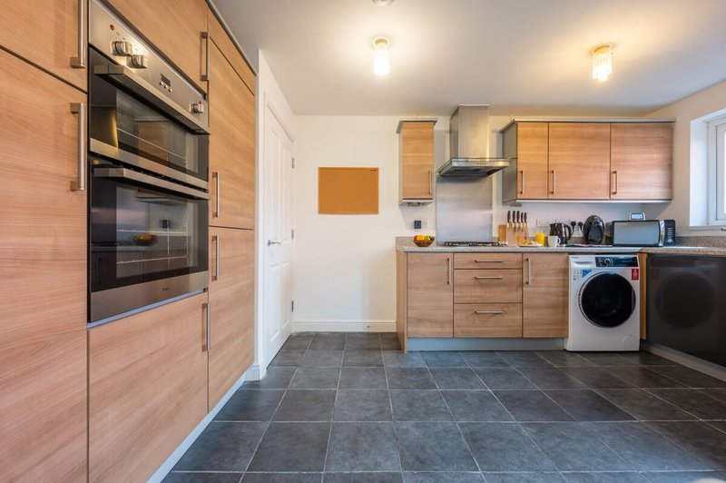 Modern kitchen with wooden cabinetry, stainless steel appliances, slate flooring and island