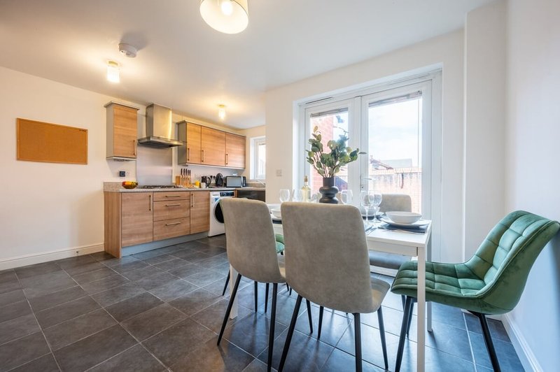 Open-plan kitchen and dining area with wooden cabinets, dining table, chairs and glass doors
