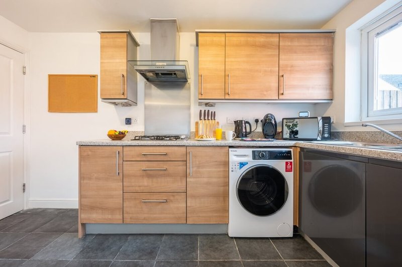 Modern kitchen with wooden cabinets, stainless steel appliances, and washing machine