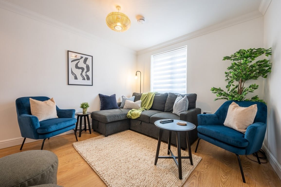 Modern living room with blue armchairs, gray sectional sofa, wooden floor and potted plant