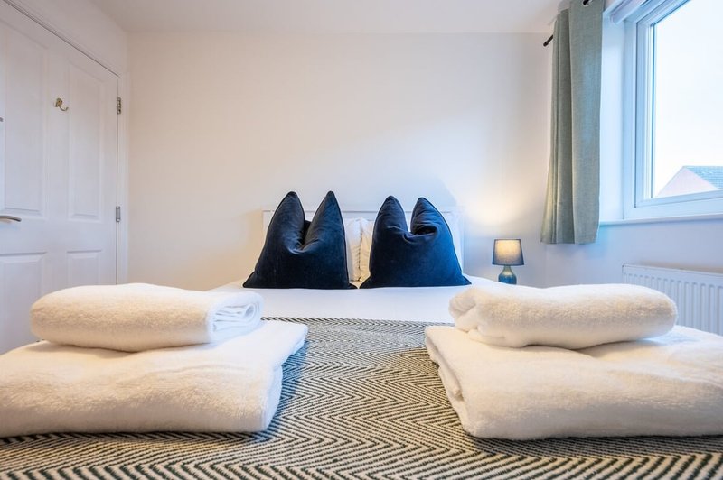 Bedroom with two single beds, white pillows, blue cushions, and striped rug