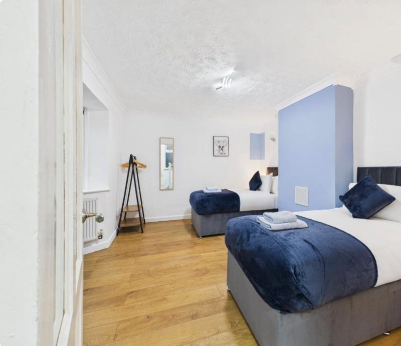 Modern bedroom with double bed, blue velvet bedding, wooden floor and minimalist decor