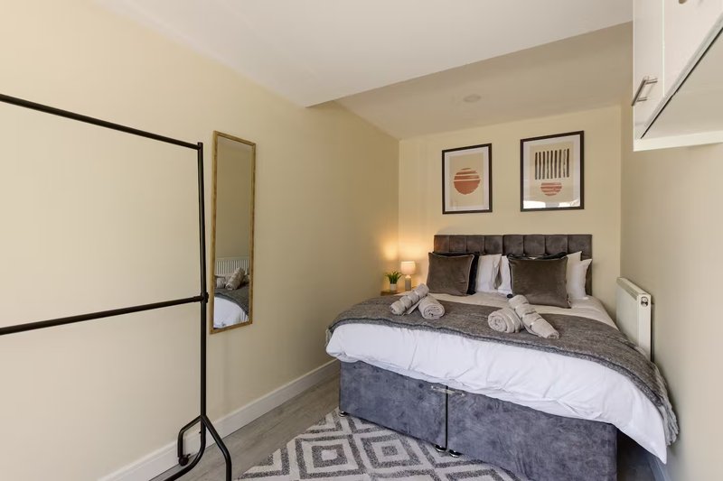 Compact bedroom with double bed, grey bedding, wall art, and cream walls