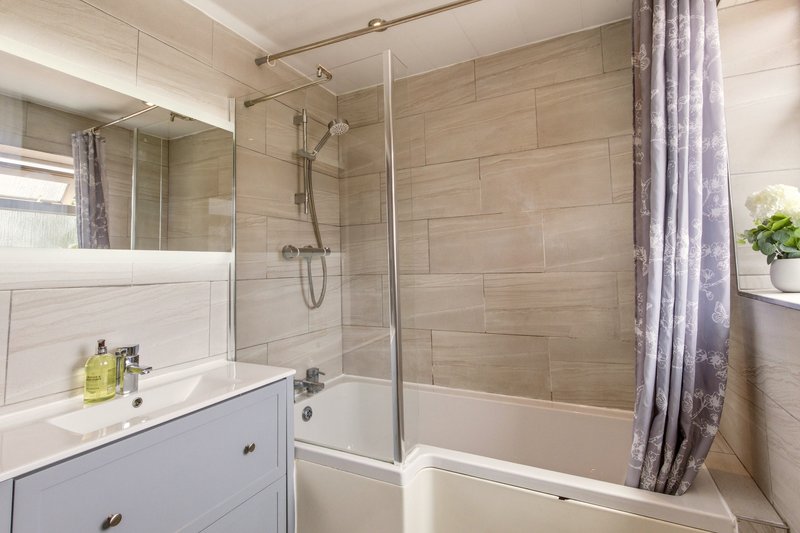 Modern bathroom with vanity sink, mirror, shower enclosure and tiled walls