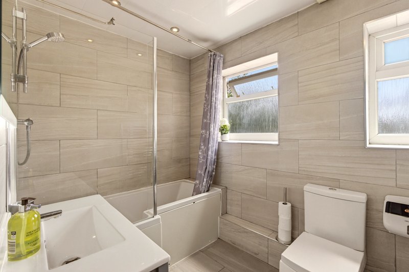 Modern bathroom with walk-in shower, toilet, sink and bright windows