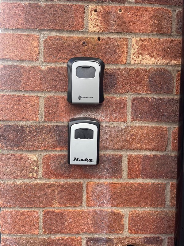 Brick exterior wall with two wall-mounted key storage boxes