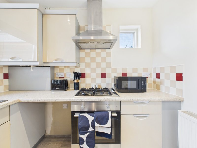 Modern kitchen with cream cabinets, gas hob, extractor hood, and geometric backtile