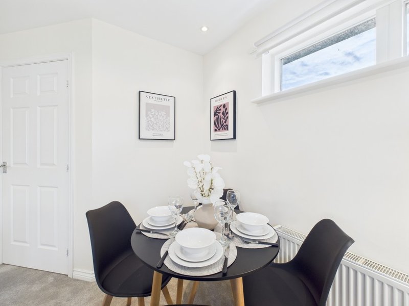 Bright dining area with round black table, black chairs, place settings and window