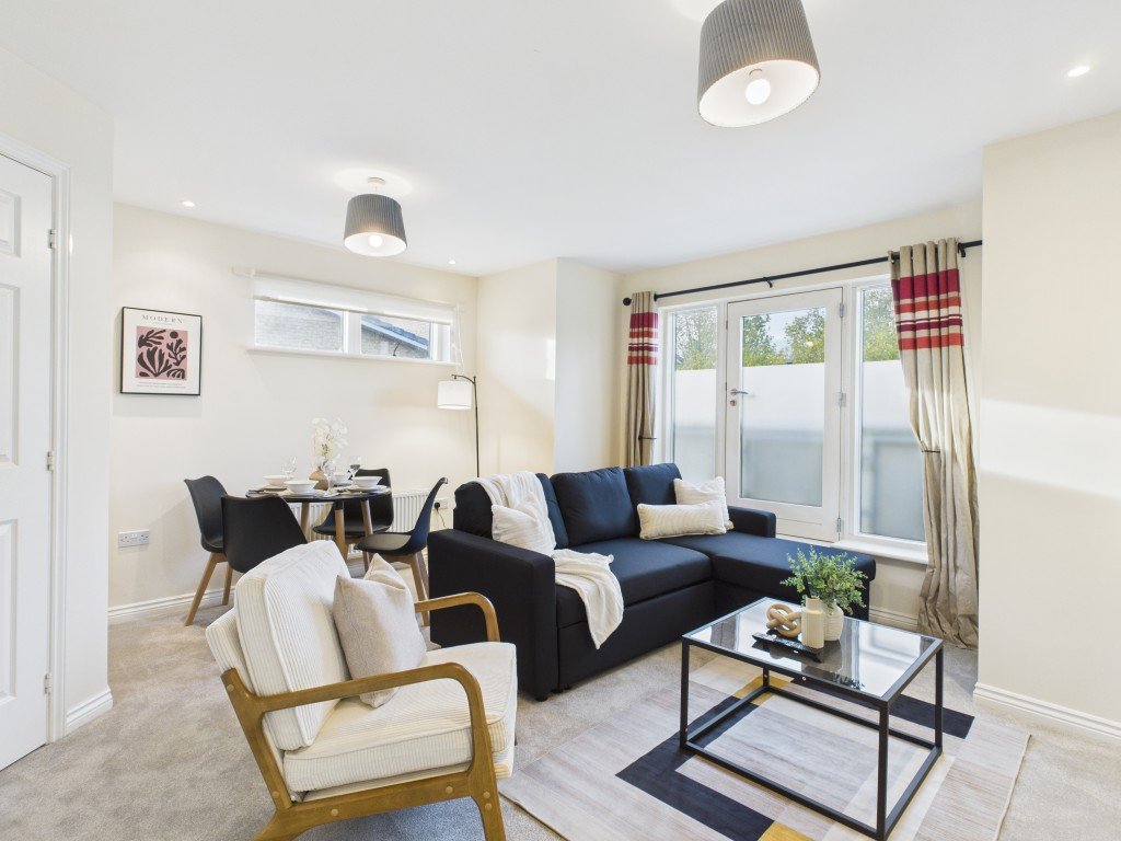 Modern living room with dark sofa, cream armchair, glass coffee table and patio doors