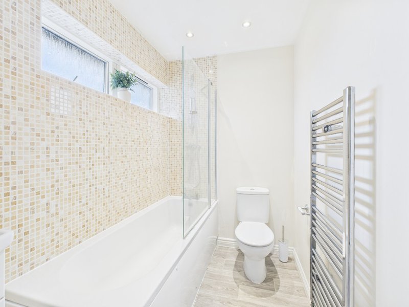 Modern bathroom with walk-in shower, toilet, heated towel rail and mosaic tile walls