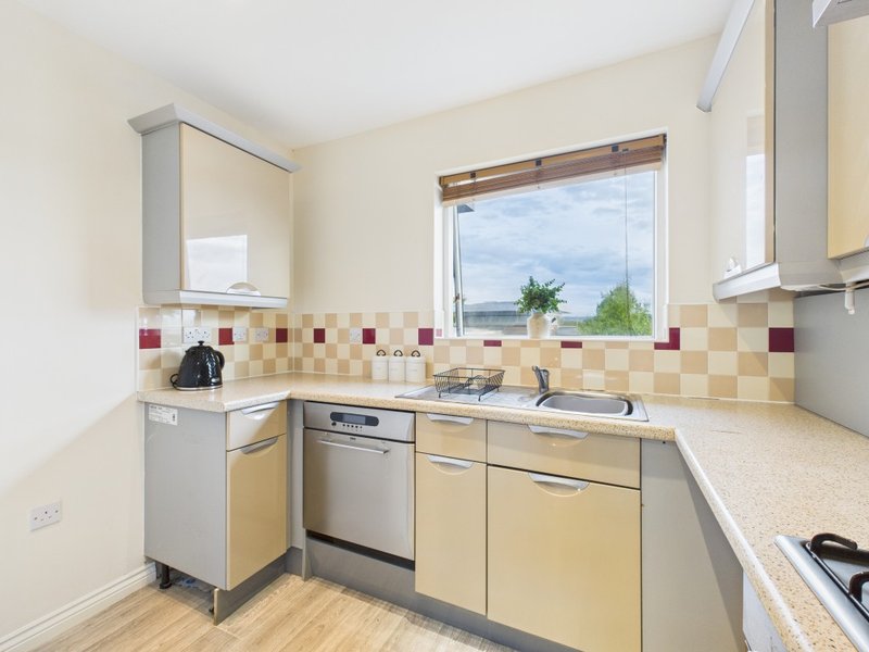 Modern kitchen with cream and yellow cabinetry, stainless steel appliances, tiled backsplash and window view