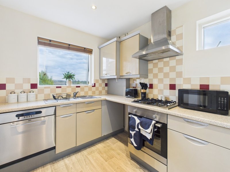 Modern kitchen with cream cabinets, stainless steel appliances, and tiled backsplash