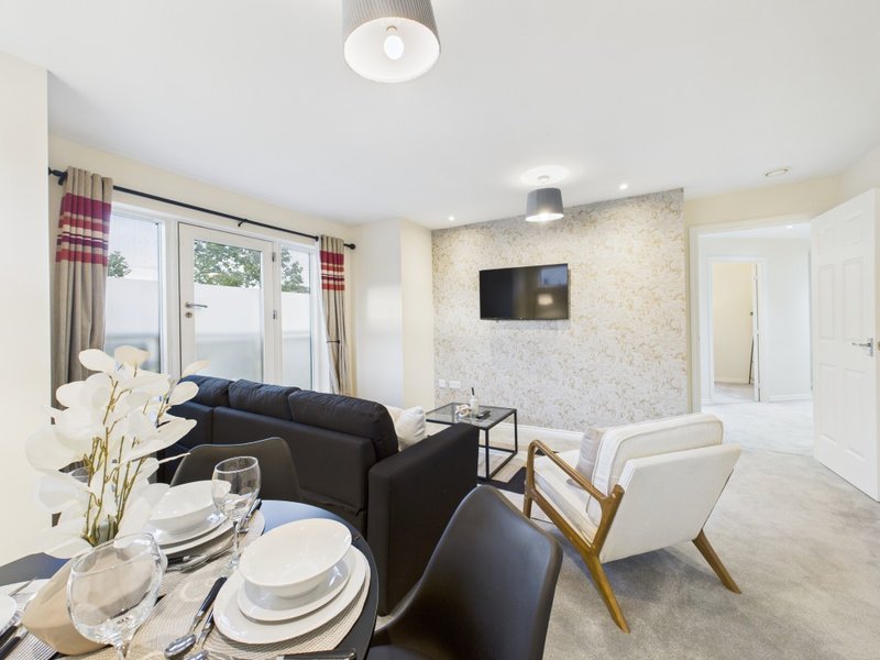 Open-plan living and dining area with black sofa, dining table, TV and garden doors