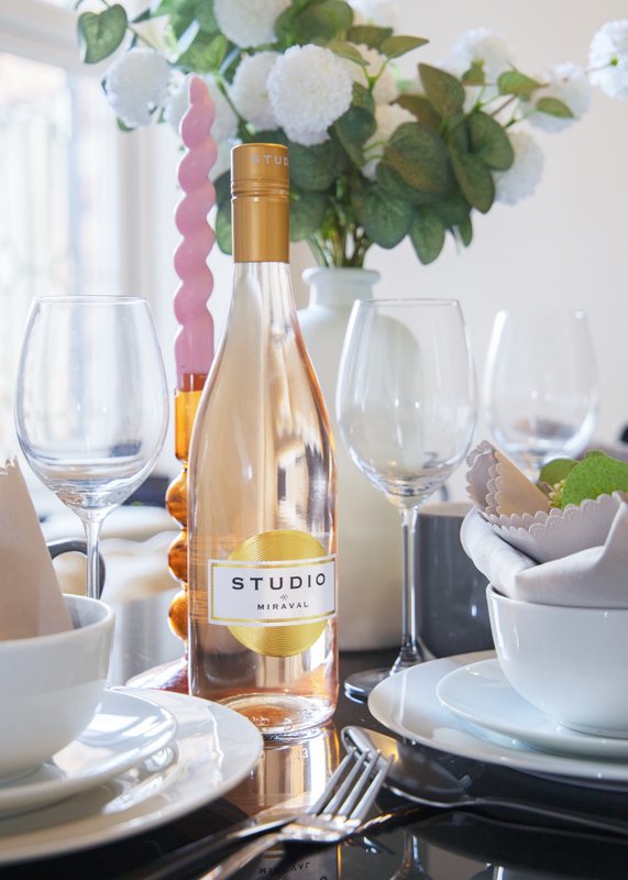 Dining table set with wine bottle, glasses, white flowers and place settings