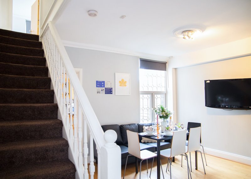 Open-plan living space with staircase, dining table, chairs and wall-mounted television