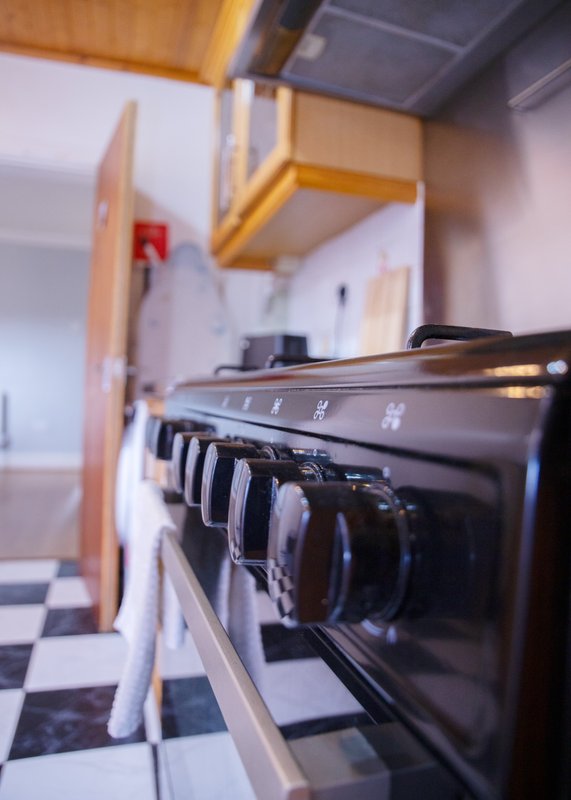 Kitchen with black electric oven, wooden cabinetry, and black-and-white tiled flooring