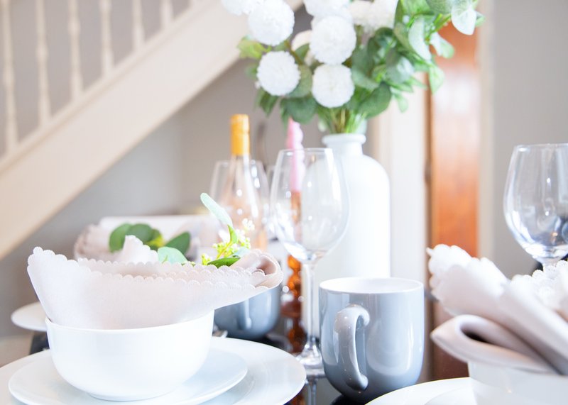 Elegantly styled dining table with place settings, flowers, wine glasses and fresh flowers in vase