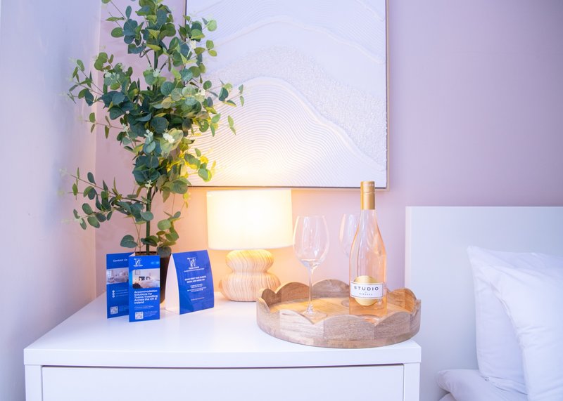 Bedside table with potted plant, lamp, toiletries and decorative items