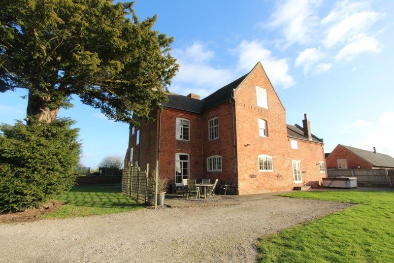 Brick farmhouse with garden, driveway, large tree and countryside setting