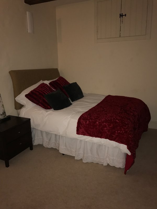 Bedroom with double bed, burgundy bedding, decorative pillows and beige headboard