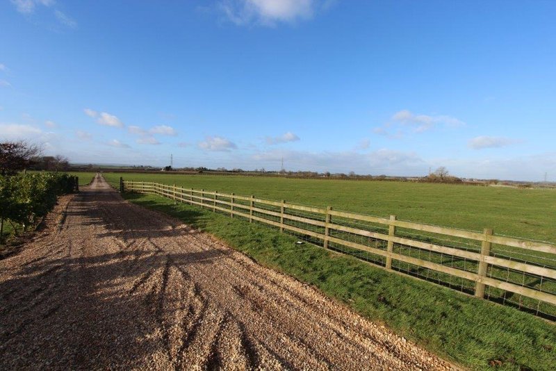 Rural property with wooden fence, plowed field and open countryside landscape