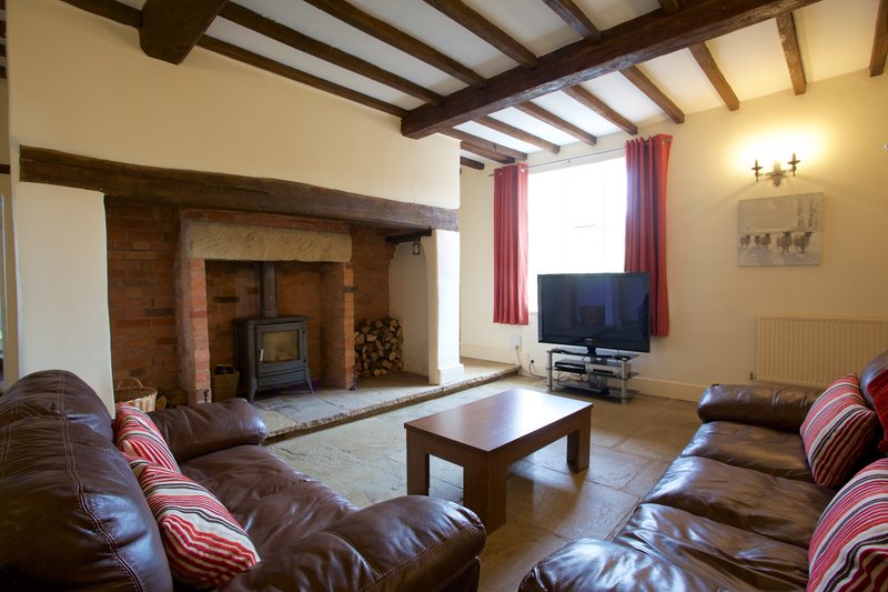 Spacious living room with exposed beams, fireplace, leather sofas and wooden coffee table