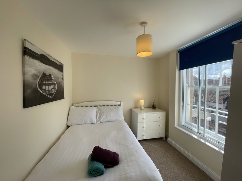 Bright modern bedroom with single bed, white bedding, bedside table, pendant light and large window