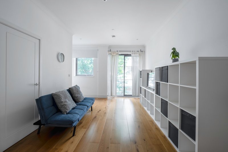 Bright open living room with blue sofa, wooden flooring, storage shelving and garden doors