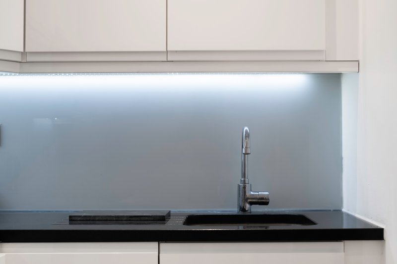 Modern kitchen with white cabinets, black countertop, and chrome faucet