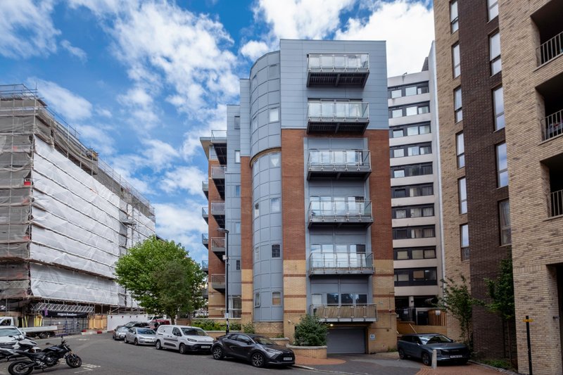 Modern multi-story residential building with brick and glass facade, street view with parked cars