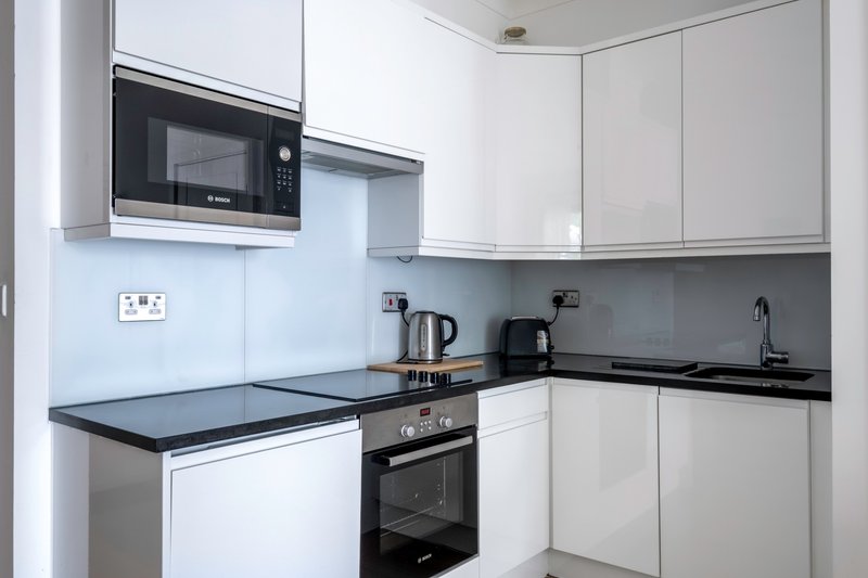 Modern white kitchen with black countertops, built-in appliances and corner layout