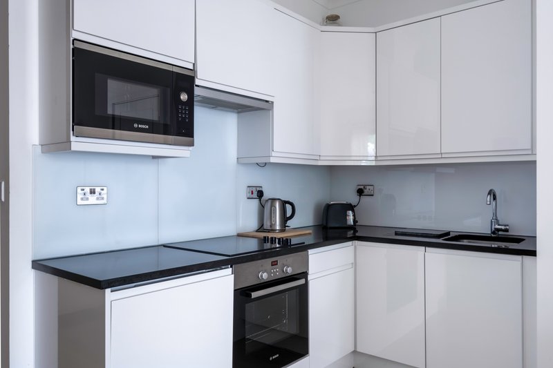 Modern kitchen with white cabinetry, black worktops, built-in microwave and oven