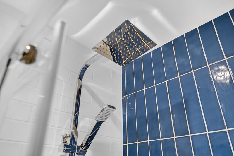 Modern bathroom shower with blue and white tiled walls, chrome fixtures and rainfall showerhead