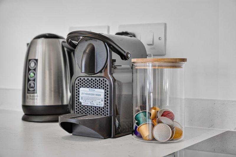 Kitchen counter with stainless steel kettle, coffee machine, and storage containers