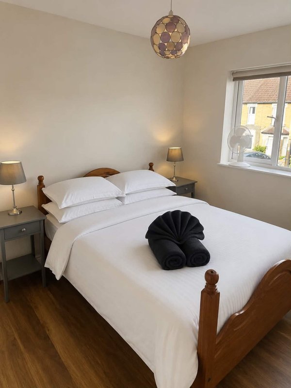 Bright bedroom with wooden bed, white bedding, black cushion, pendant light and bedside tables
