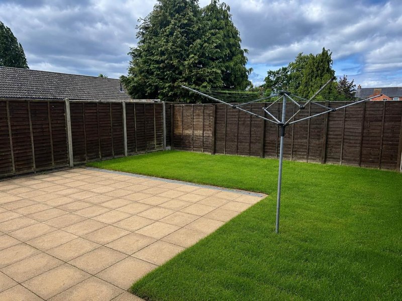 Garden with paved patio area, lawn, wooden fencing and rotary clothesline