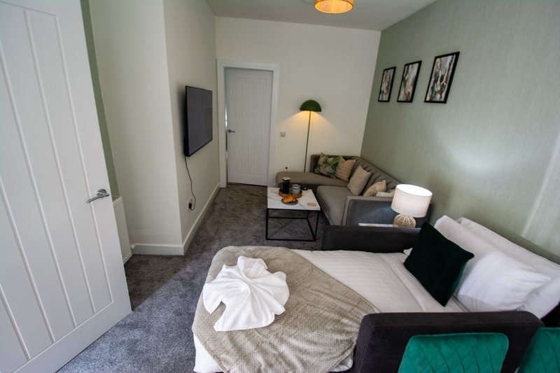 Bedroom with double bed, seating area, TV, lamp and framed wall art