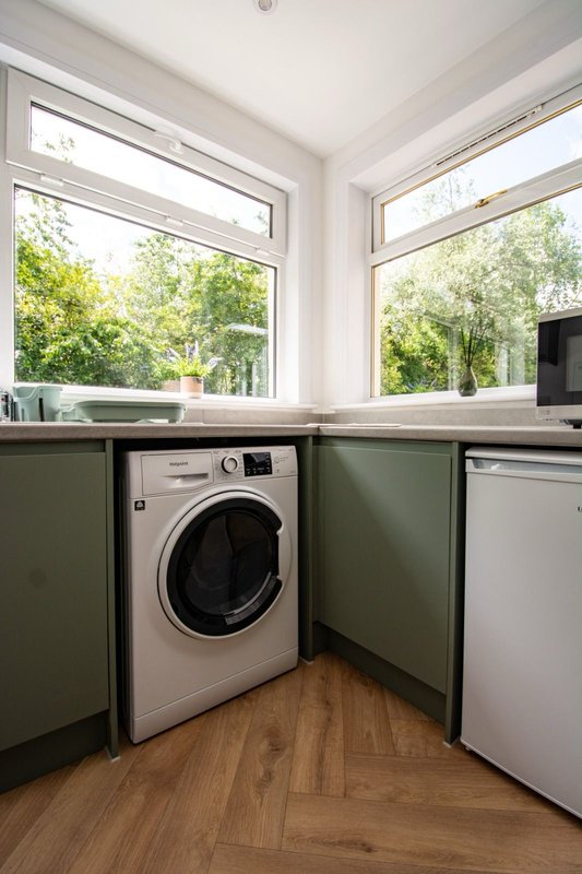 Laundry room with washing machine, dishwasher, and large windows overlooking garden