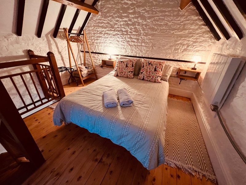 Bedroom with double bed, wooden floor, exposed beams and blue bedding